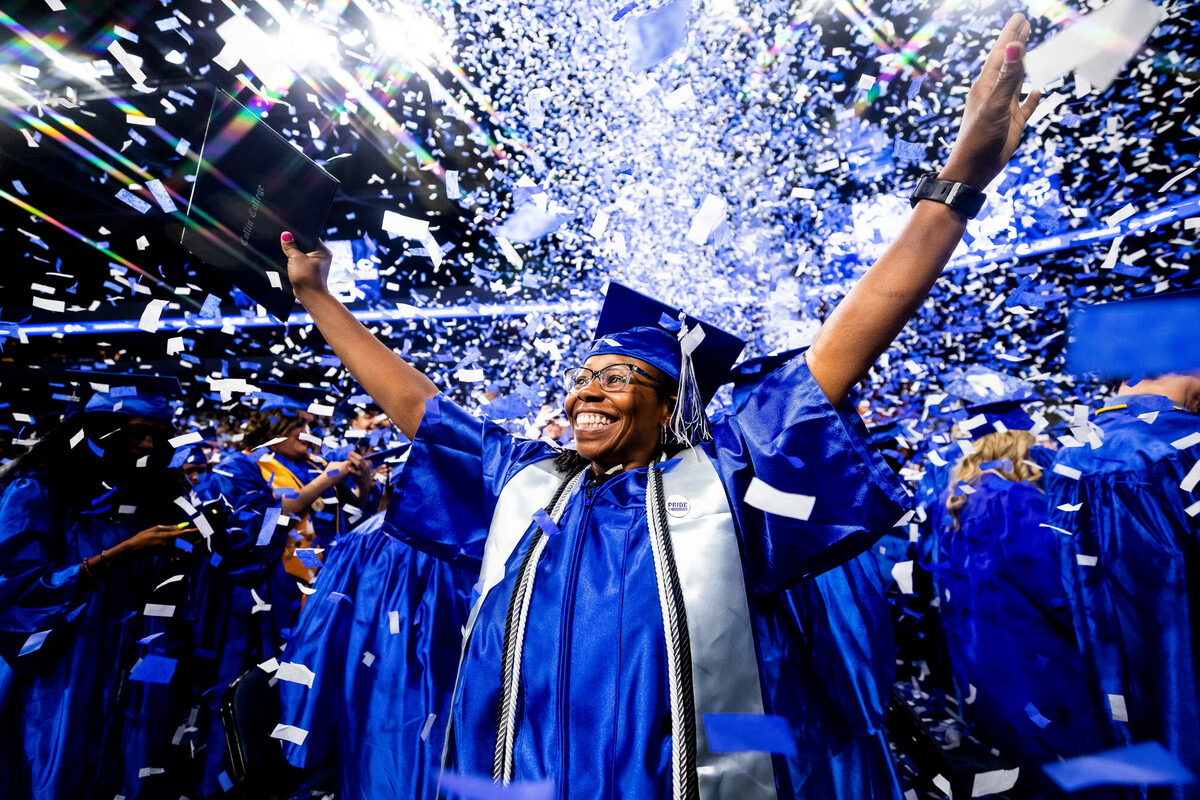 student in graduation robe as confetti is in the air