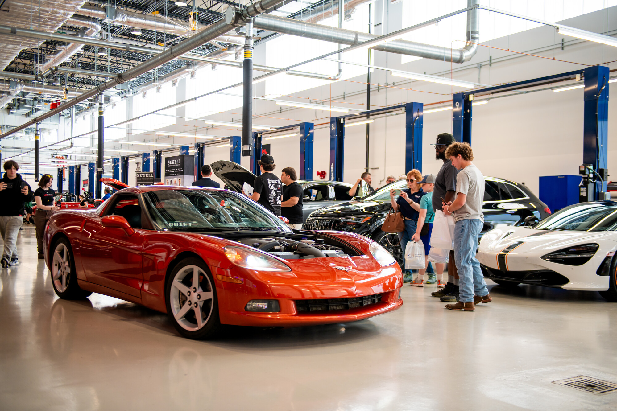 red car on display, attendees observing 
