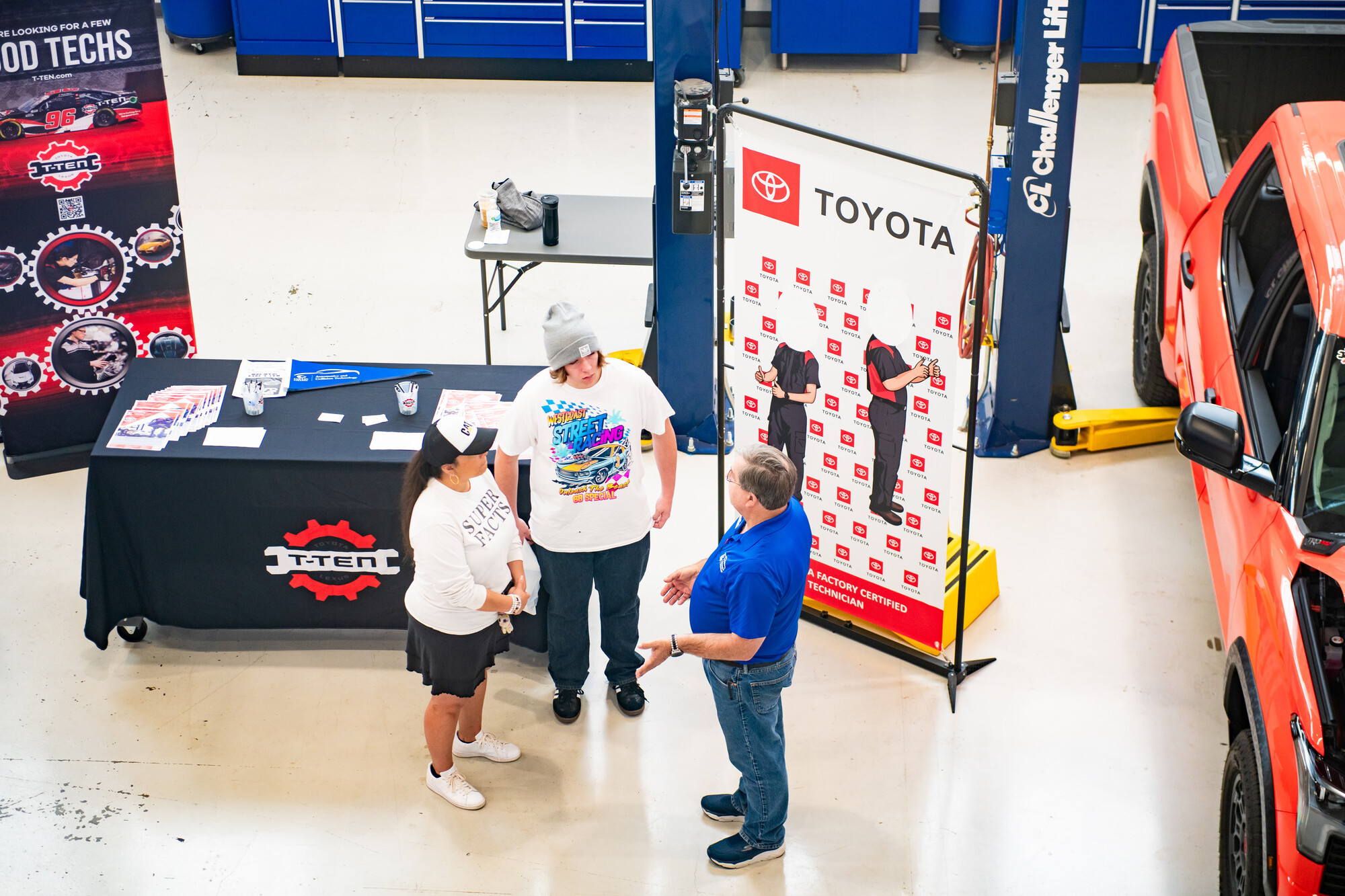 three adults talk in front of informational table 