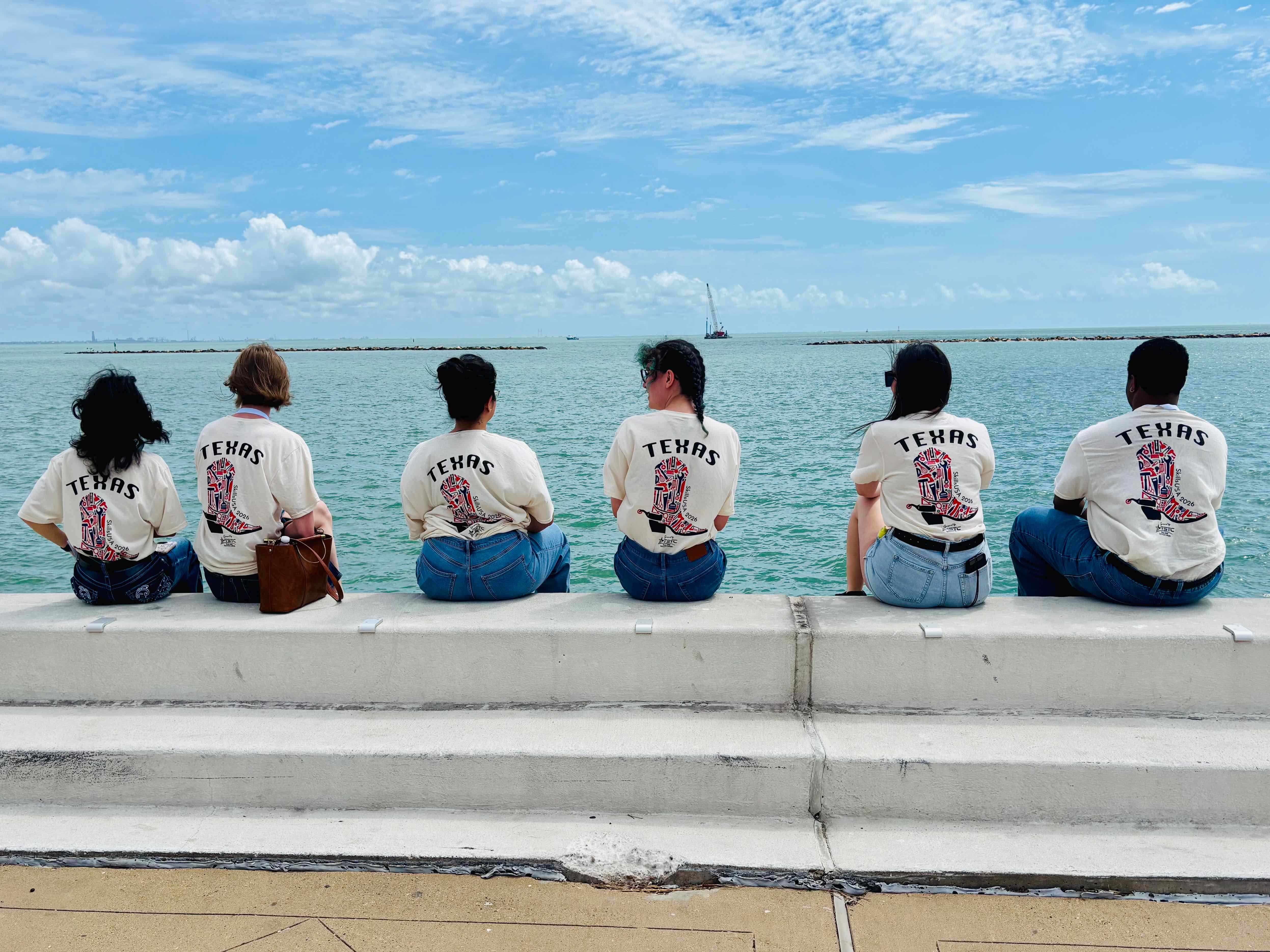Group of students pose for picture in front of water coast. 