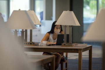 A student wearing a mask works quietly inside the Wylie Campus library.